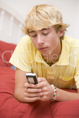 Teenage Boy Lying On Bed Using Mobile Phone