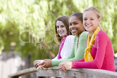 Teenage Girls Leaning On Wooden Railing