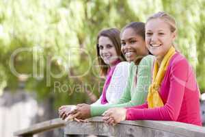 Teenage Girls Leaning On Wooden Railing
