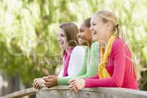 Teenage Girls Leaning On Wooden Railing