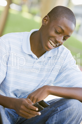 Teenage Boy Sitting Outdoors Using Mobile Phone