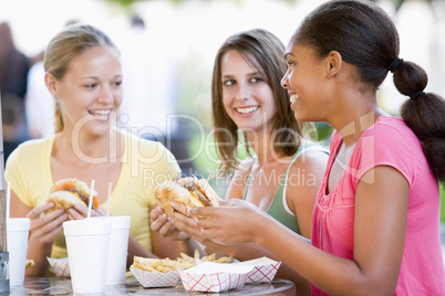 Teenage Girls Sitting Outdoors Eating Fast Food