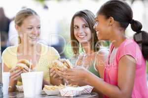 Teenage Girls Sitting Outdoors Eating Fast Food