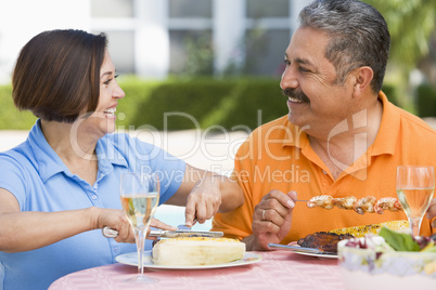 Couple Enjoying A Barbequed Meal In The Garden