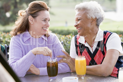 Two Female Friends Enjoying A Beverage By A Golf Course