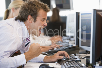 Ein Banker sitzt jubelnd vor seinem Computer