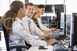Vier Arbeitskollegen sitzen nebeneinander vorm PC