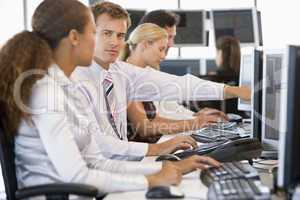 Vier Arbeitskollegen sitzen nebeneinander vorm PC