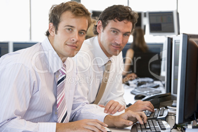 Zwei junge Männer sitzen im Büro bei der Arbeit