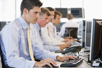 Vier Männer nebeneinander vor Bildschirmen