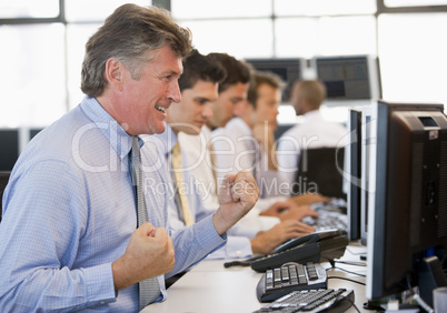Ein älterer Herr jubelt vor seinem Bildschirm im Büro