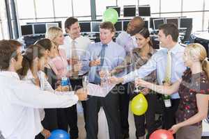 Kollegen feiern im Büro mit Sekt und Luftballons