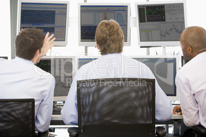 Drei Männer sitzen am Schreibtisch vor Bildschirmen