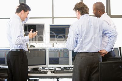 Drei Männer stehen im Büro vor Bildschirmen