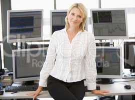 Blonde Frau in weißer Bluse sitzt auf Schreibtisch