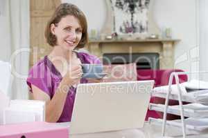 Junge Dame sitzt mit Tasse Kaffee vor Notebook