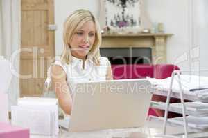 Eine junge blonde Frau sitzt am Notebook