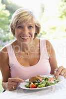 Frau isst von einem Salatteller mit Fleischbeilage