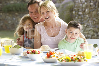 Junge Familie sitzt im Freien am gedeckten Tisch