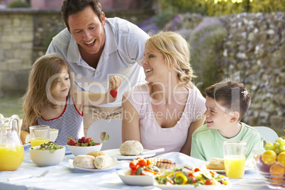 Eine junge Familie sitzt am gedeckten Tisch