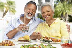 Ein älteres Paar sitzt im Freien an einem gedeckten Tisch