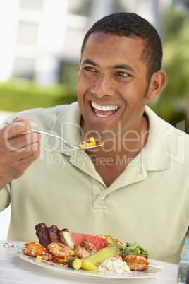 Ein junger Mann sitzt vor einem gemischten Teller