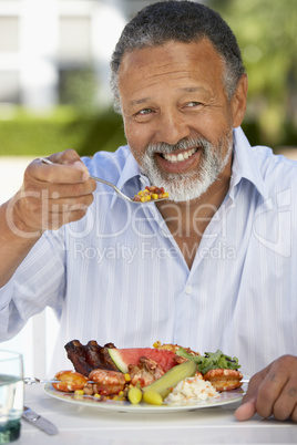 Ein älterer Herr sitzt vor einem gemischten Teller