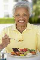 Eine ältere Dame sitzt vor einem leckeren Teller