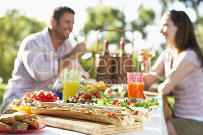 Junges Paar sitzt im Freien an einem gedeckten Tisch