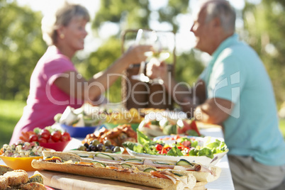 Älteres Paar sitzt am gedeckten Tisch im Freien