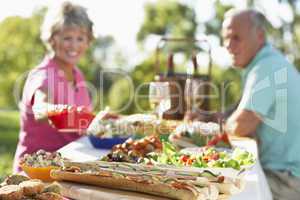 Ein älteres Paar sitzt im Freien an einem gedeckten Tisch