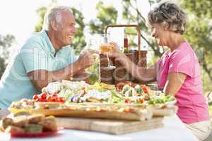Älteres Paar sitzt am gedeckten Tisch im Freien