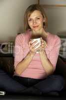 Woman Relaxing With Cup Of Coffee Watching Television