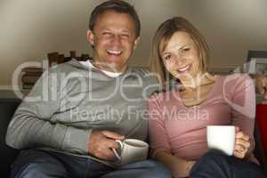 Couple With Coffee Mugs Watching Television