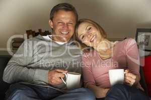 Couple With Coffee Mugs Watching Television
