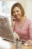 Woman Using Computer And Talking On Phone