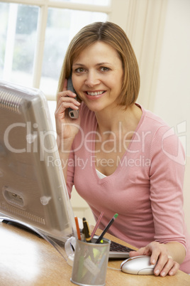 Woman Using Computer And Talking On Phone