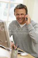 Man Using Computer And Talking On Phone