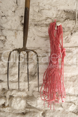Mistgabel und Seil hängen an der Wand