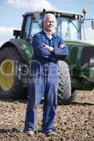 Ein Landwirt steht im Blaumann vor seinem Traktor