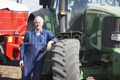 Ein Landwirt lehnt an seinem Traktor auf dem Feld