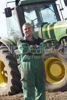 Ein Bauer steht mit verschränkten Armen vor einem Traktor