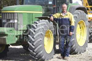 Ein Bauer steht neben seinem Traktor