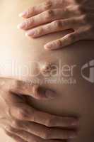 Schwangere Frau legt zärtlich die Hände auf den Bauch