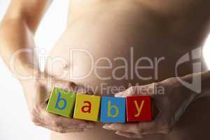 Werdende Mutter hält Buchstaben an ihren Bauch