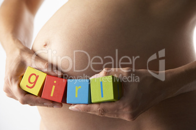 Werdende Mutter hält Buchstaben an ihren Bauch