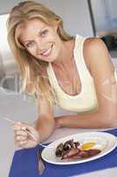 Eine blonde Frau sitzt vor einem gemischten Teller