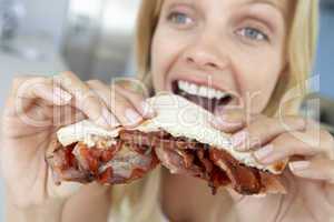 Eine blonde Frau beißt in ein Sandwich