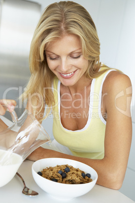 Blonde Frau sitzt am Tisch mit Schale Corn Flakes