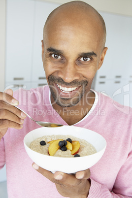 Mann hält Schüssel mit Grießbrei und Obst